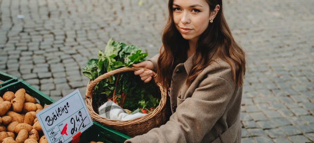 Young woman shopping at Erfurt farmers market, holding basket with fresh vegetables. Capturing local shopping culture.
