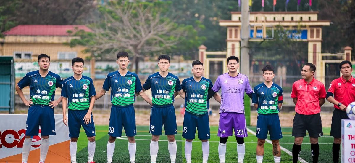 Soccer players and referees standing together on a field in Hà Nội, Vietnam.